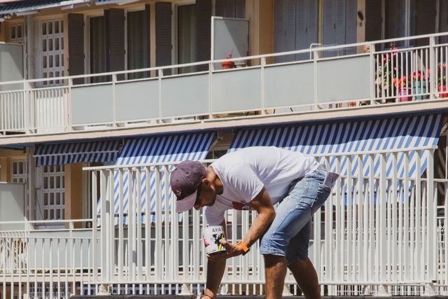 Worker painting a white stripe line on asphalt